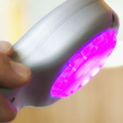 A Low Level Laser Therapy tool with a purple light emitting from it.
